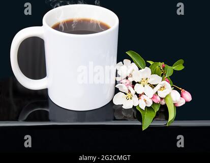 Tasse à café blanche avec fleurs de cerisier sur fond noir brillant dans cette maquette photo de produit stylisée. Café noir chaud à la vapeur avec l'espace de copie activé Banque D'Images