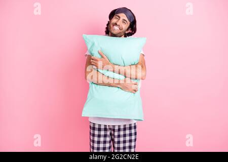 Photo d'un jeune homme souriant et souriant qui se sent embrasser l'oreiller juste réveillé isolé sur fond de couleur rose Banque D'Images