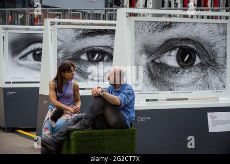 Londres, Royaume-Uni. 10 juin 2021. Un couple s'assoit devant une installation d'œuvres de l'artiste français JR pour le projet Inside Out devant le stade Wembley, avant le début de l'Euro 2020. Beaucoup des sujets dans les travaux sont des travailleurs du NHS pendant la pandémie de coronavirus en cours. Credit: Stephen Chung / Alamy Live News Banque D'Images