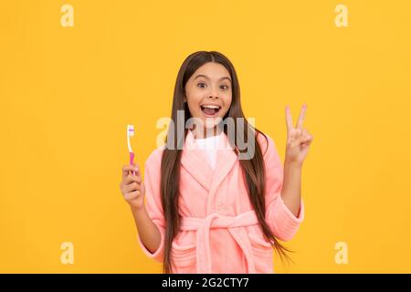 bonne surprise teen fille à la maison terry peignoir tenir brosse à dents montrer la paix geste, l'enfance Banque D'Images