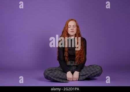 Femme avec les yeux fermés sur fond violet Banque D'Images