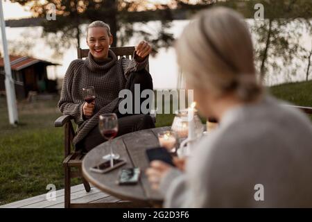 Des amies assises sous le porche et buvant du vin Banque D'Images