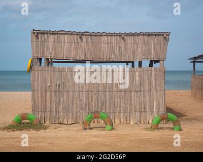 Arrière-plan de la mer à la plage de Mayapo avec un petit magasin écologique fait de feuilles de Banana séchées et des billes et une clôture faite de pneus peints verts Banque D'Images