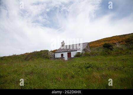 Un petit cottage traditionnel gallois connu sous le nom de Carreg Bach sur l'île Ynys Enlli / Bardsey avec des murs en pierre blanchie à blanc et des fenêtres de porte avant peintes en rouge Banque D'Images