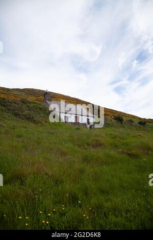 Un petit cottage traditionnel gallois connu sous le nom de Carreg Bach sur l'île Ynys Enlli / Bardsey avec des murs en pierre blanchie à blanc et des fenêtres de porte avant peintes en rouge Banque D'Images