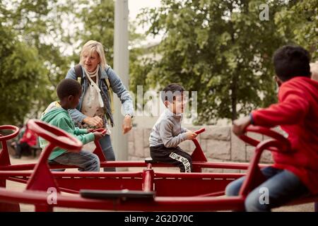 Les enfants qui tournent sur le joyeux font du tour Banque D'Images