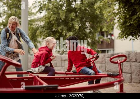 Les enfants qui tournent sur le joyeux font du tour Banque D'Images