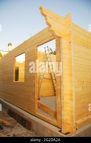 Une maison en bloc préfabriquée en bois (sapin) partiellement construite sur un site de construction domestique. La porte avant est visible au premier plan. Udine, Italie Banque D'Images