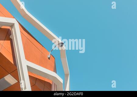 Caméra de vidéosurveillance ronde extérieure sur le toit du bâtiment, fond bleu ciel. Banque D'Images