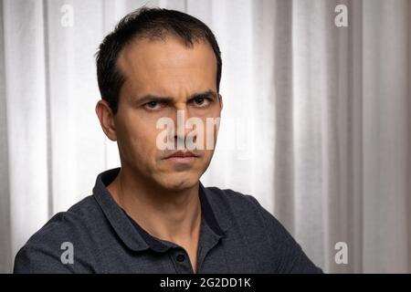 Homme mature (44 ans) en séance photo avec polo bleu foncé, faisant plusieurs visages. Banque D'Images