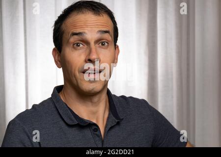 Homme mature (44 ans) en séance photo avec polo bleu foncé, faisant plusieurs visages. Banque D'Images