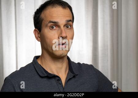 Homme mature (44 ans) en séance photo avec polo bleu foncé, faisant plusieurs visages. Banque D'Images