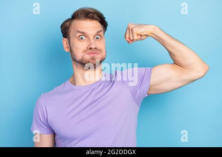 Portrait de la personne positive excitée tenir souffle joues bras Flex montrent biceps isolés sur fond bleu de couleur Banque D'Images