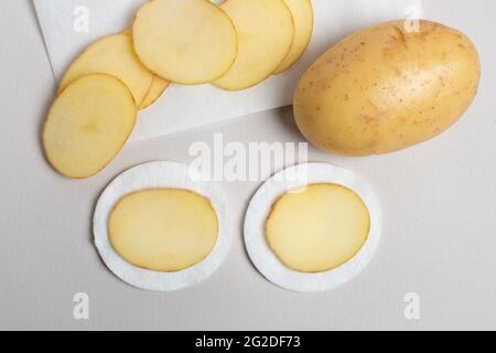 Tranches de pommes de terre préparées pour les procédures cosmétiques. Pommes de terre - un ingrédient de beauté incroyable. Soin fait maison. Banque D'Images
