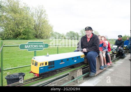 Un chauffeur de train emmène les enfants dans un train miniature amusant sur les voies. Banque D'Images