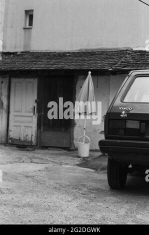 Voiture Yugo devant un parasol dans un seau en plastique devant l'ancien bâtiment Banque D'Images