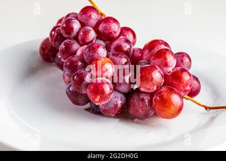 Belle close-up de grappe de raisins rouges (encres) sur la table. Et crus, frais et gouttes d'eau. Banque D'Images