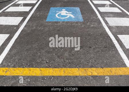 Parking extérieur pour fauteuils roulants. Symbole de signalisation routière handicapés peint sur l'asphalte Banque D'Images