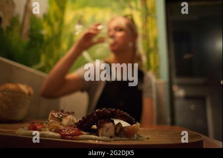 Une femme boit un verre de vin en arrière-plan d'une assiette de délicieux fruits de mer dans un restaurant de Barcelone Banque D'Images