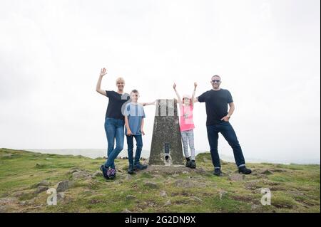 Une famille debout près d'un point de trig sur une promenade à la campagne près de Ludlow, Shropshire. Banque D'Images