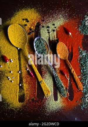 Vue de dessus des cuillères en métal de tailles multiples disposées côte à côte avec différentes épices Banque D'Images