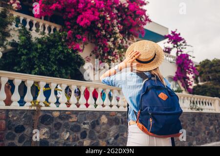 Femme voyageur appréciant bougainvilliers fleurs en Grèce. Bonne femme marchant portant un chapeau et un sac à dos Banque D'Images