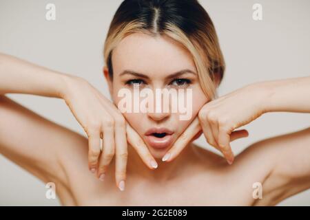 Femme faisant des massages de yoga du visage et des exercices rajeunissants facebuilding avec ses mains Banque D'Images