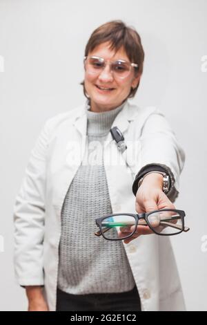 Un employé d'un opticien remet à un client de nouvelles lunettes, vues dans la première personne. Les lunettes sont au point et le visage de l'optométriste est hors point. Banque D'Images