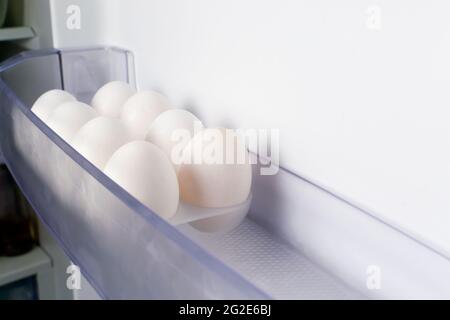 Les œufs de poulet blancs sont dans un moule sur la porte du réfrigérateur. Concept de nutrition saine. Copier l'espace. Orientation horizontale. Banque D'Images