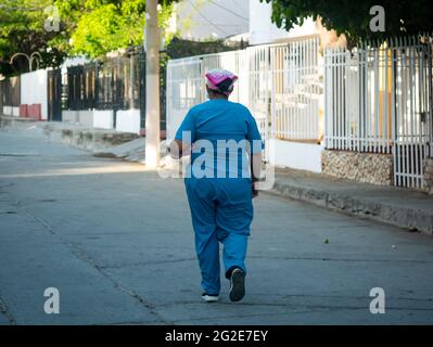 Santa Marta, Magdalena, Colombie - Mai 22 2021: Une femme latine vêtue de bleu clair avec un foulard marche au milieu de la rue tôt dans le Morn Banque D'Images