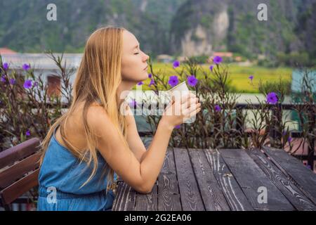 Une femme boit du café le matin sur fond de collines à Ninh Binh, Tam COC. Reprise du tourisme au Vietnam après la quarantaine coronovirus Banque D'Images