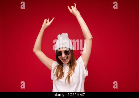 Photo de belle positive jeune femme blonde sombre portant des vêtements décontractés et des lunettes de soleil élégantes isolées sur fond coloré mur look Banque D'Images