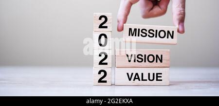 Homme d'affaires main tenant cube en bois avec texte 2022 Mission, Vision et valeur sur fond de table. Résolution, stratégie, solution, objectif, entreprise et Banque D'Images