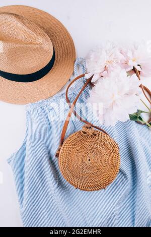 Vêtements d'été mode pour femmes, accessoires. Chapeau de paille féminin élégant, robe bleue, sac en rotin, pivoine Banque D'Images