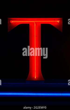 Lettre T lumineuse rouge avec soulignement bleu la nuit Banque D'Images