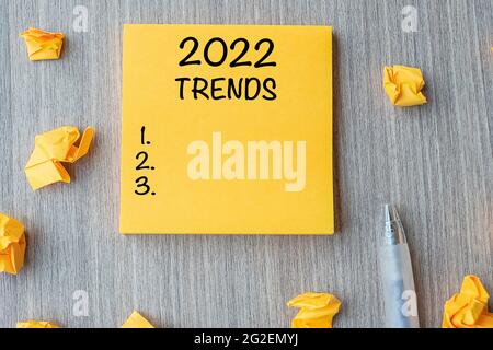 2022 tendances mot sur note jaune avec stylo et papier froissé sur fond de table en bois. Nouvelle année Nouveau départ, résolutions, stratégie et concept d'objectif Banque D'Images