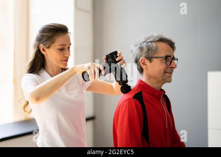 Pistolet de massage, traitement de récupération des épaules à l'aide de la machine Banque D'Images