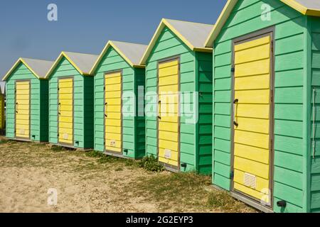 Huttes de plage colorées jaune et verte sur le front de mer à Littlehampton, West Sussex, Angleterre. Banque D'Images