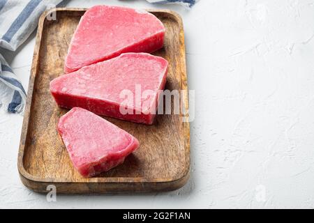 Steaks de thon surgelé, sur plateau en bois, sur fond de pierre blanche , avec espace de copie et espace pour le texte Banque D'Images