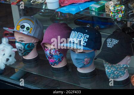 Masques pour le visage à vendre dans la vitrine du magasin à Bournemouth, Dorset Royaume-Uni en juin - têtes de mannequin portant des casquettes de baseball et des masques pour le visage masque pour le visage Banque D'Images