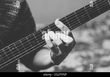 Photo en noir et blanc d'un musicien jouant de la guitare. Doigts sur un fretboard de guitare gros plan Banque D'Images