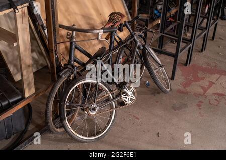 Gros plan d'une vieille bicyclette sur une salle de stockage avec d'autres cadres métalliques et bois inutilisés Banque D'Images