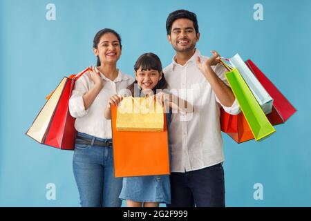 UNE FAMILLE HEUREUSE SE POSANT AVEC ENTHOUSIASME DEVANT L'APPAREIL PHOTO APRÈS AVOIR FAIT DU SHOPPING Banque D'Images