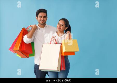 UN JEUNE COUPLE SE POSE AVEC DES SACS À PROVISIONS À LA MAIN Banque D'Images