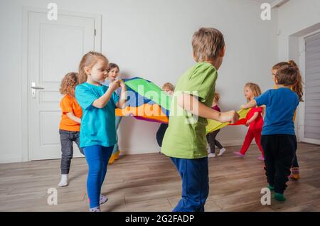 Jeux avec verrière colorée, enfants assis sous parachute Banque D'Images