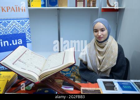 Fille musulmane souriante portant le hijab présentant la littérature islamique dans la librairie, Quran placé sur le comptoir. Réserve Fair Knyzhkovyi Arsenal. 23 mai 20 Banque D'Images