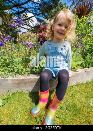 Une jeune fille de trois ans s'est assise dans le jardin en été, à Devon, au Royaume-Uni Banque D'Images