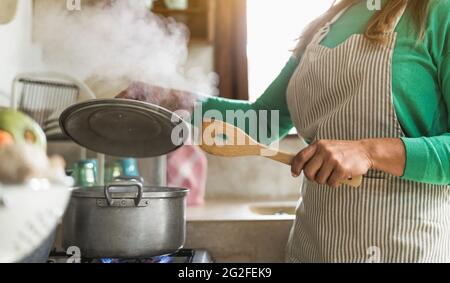 Femme d'âge latin cuisant dans une ancienne cuisine - mère préparant le déjeuner pour la famille à la maison - Focus sur les doigts Banque D'Images