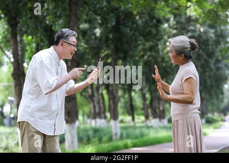 Un vieux couple heureux prenant des photos avec un téléphone portable dans le parc photo de haute qualité Banque D'Images