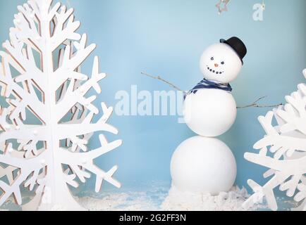 Bonhomme de neige sur fond bleu avec décorations suspendues et montage de studio de photo d'arbre blanc Banque D'Images